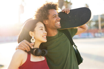 Beautiful couple having fun outdoors. Portrait of loving couple with skateboard