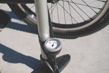 pump with a manometer close-up stands against the background of a bicycle wheel on the street