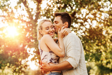 Fototapeta premium summer holidays, love and people concept - happy young couple kissing and hugging outdoors