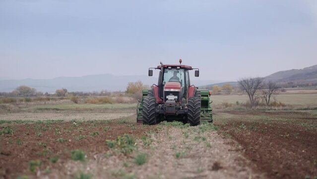 Farmer with tractor seeding crops at field, slow motion