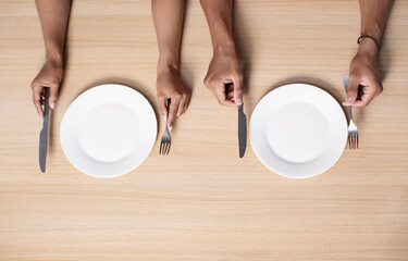 Hands of hungry millennial african american woman and man hold cutlery near empty plates on table