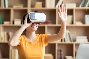 Smiling surprised japanese female in vr glasses plays in online game and touches empty space with hand