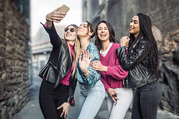 Four women best friends taking selfies on the street - generation z girls having fun outdoors...