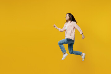 Fototapeta na wymiar Full body side view young happy sporty fun woman she 30s wears striped shirt white t-shirt jump high run fast hurry up isolated on plain yellow background studio portrait. People lifestyle concept