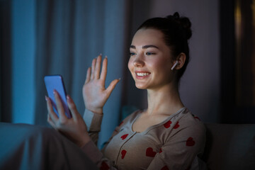 technology, bedtime and people concept - happy smiling teenage girl with smartphone and earphones...