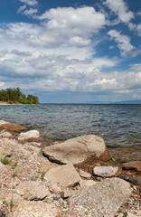 Baikal Lake in summer. The rocky coast of the Small Sea with clear water and a green forest in the distance on a sunny day. Summer landscape. Travel and recreation on the lake