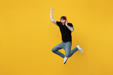 Full body young fun bearded tattooed man 20s he wears casual black t-shirt cap headphones listen to...