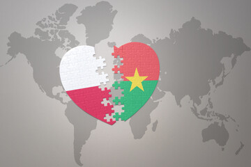 puzzle heart with the national flag of burkina faso and poland on a world map background.Concept.