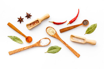Variety of colorful spices and herbs in wooden spoons on kitchen table, top view