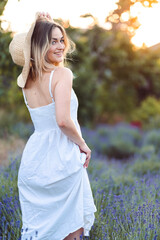 Close-up Portrait of Smiling Girl Standing with her Back, Hand Near her Hat on Lavender Meadow.