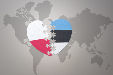 puzzle heart with the national flag of estonia and poland on a world map background.Concept.