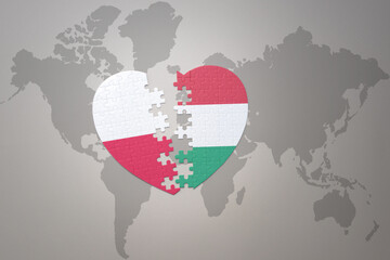 puzzle heart with the national flag of hungary and poland on a world map background.Concept.