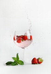 Strawberry mocktail with mint in  glass with splashing at white background. Refreshing summer non-alcoholic drink with berries. Front view.