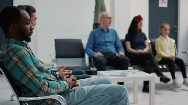 Portrait of african american patient sitting on chair in waiting room at medical facility, waiting to start consultation appointment at hospital reception. Diverse people in clinical lobby.