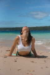 Brunette girl in swimsuit relaxing at the water. Sexy female in a white bikini on a tropical beach. A curly woman enjoys during her summer holiday in the Philippines