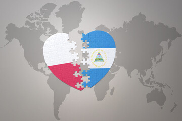 puzzle heart with the national flag of nicaragua and poland on a world map background.Concept.