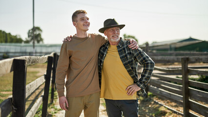 Grey hair male farmer and grandson hugging on farm