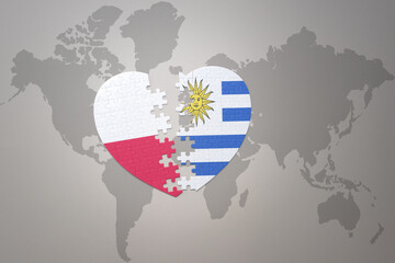 puzzle heart with the national flag of uruguay and poland on a world map background.Concept.