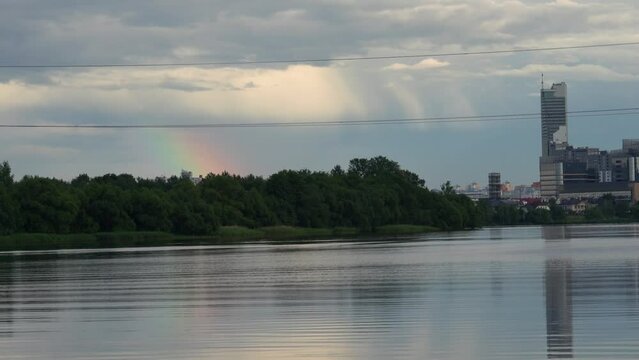General view of the city of Minsk (the capital of the Republic of Belarus). After the rain, a bright rainbow is visible over modern buildings. Skyscrapers are reflected in the Drozdy reservoir