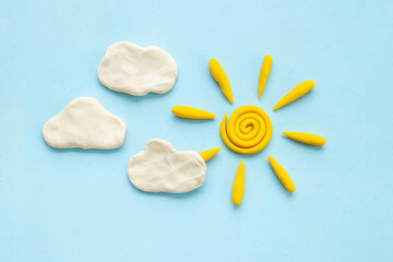 Weather forecast concept with plasticine sun and clouds, top view