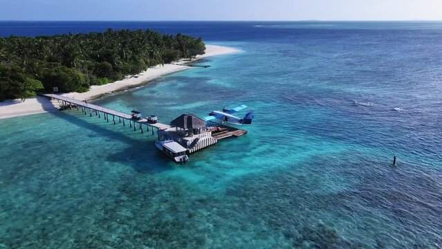 AERIAL: Docked Seaplane to a Tropical Island in Indian Ocean, Vakkaru, Maldives. Seaplane transporting passengers to small islands from Male Airport