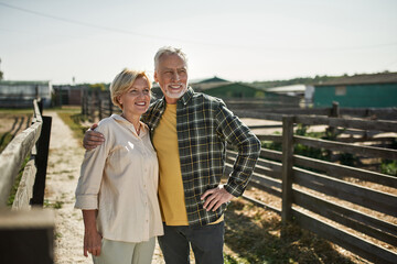 Mature farmer couple hug and look away on farm © Svitlana