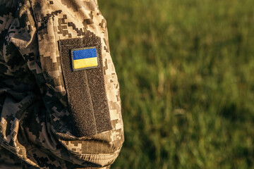 Close up velcro patch with flag of Ukraine on military uniform soldiers arm. Armed Forces of...