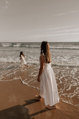 Fototapeta na wymiar Mother walking near playing daughter on beach