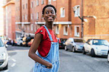 Young black African model woman crossing the street of a city very smiling.