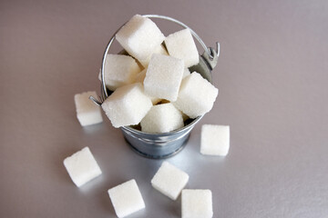 A small bucket with cubes of pressed sugar on a gray background.