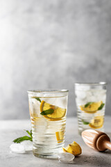 Lemonade or mojito cocktail with lemon, mint and wooden juicer, summer iced refreshing drink on gray background