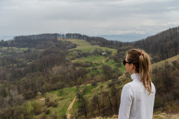 Beautiful mountains and standing young woman on top hills. Landscape with mountain peak, forest. Travel concept