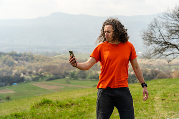 Young man making selfie on mobile phone on the hill