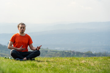 Fototapeta na wymiar Young man do yoga on the mountain peak