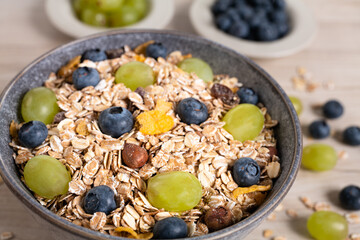 Eine Schale mit Frühstücks-Müsli und frischen Heidelbeeren und Weintrauben