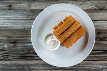 Bread croutons with mayonnaise sauce on a white plate. Wooden background, rustic style.