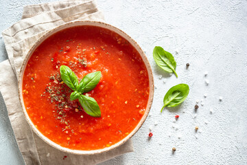 Tomato soup in craft bowl. Traditional vegetable soup. Top view on white background.