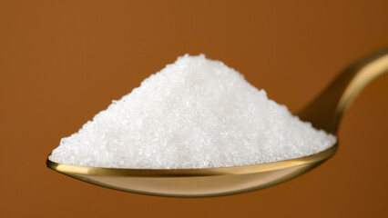 White sugar in golden spoon, close up