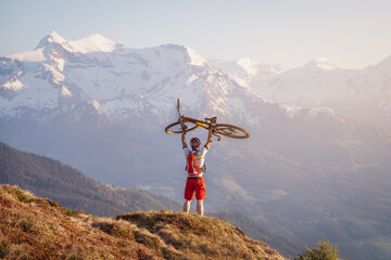 Male mountainbiker in the mountains holding his bike