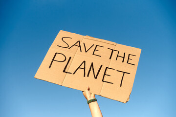 A Cardboard Signs saying Save the Planet held by two hands on sky background