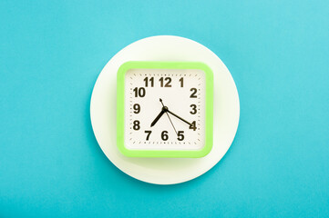 Minimal still life concept green analog clock on a white plate.