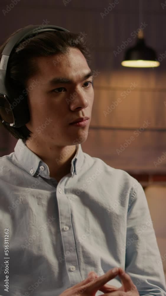 Poster vertical video: company employee listening to podcast episode or webinar, using computer to do remot