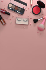 Top view makeup brushes, cosmetics and flowers on pink background. Copy space for your text