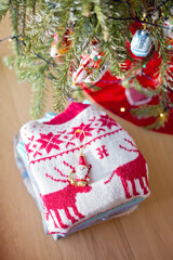 Christbaumschmuck auf einem Stappel von Pullovern  unter einem Weihnachtsbaum