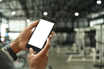 Man hands holding smartphone on blurred gym background. Blank screen for your advertise text