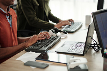 Cropped image of skilled focused guys coding at office desk