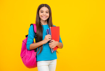 Happy teenager portrait. Schoolgirl, teenage student girl hold book on yellow isolated studio background. School and education concept. Back to school. Smiling girl.