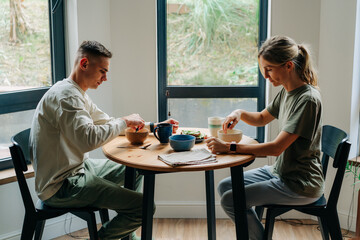 Man and woman having breakfast with porridge with berries at home