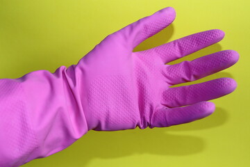 a human hand with pink rubber glove on the yellow background