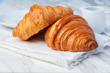 Fresh croissants bread on marble table. French breakfast.